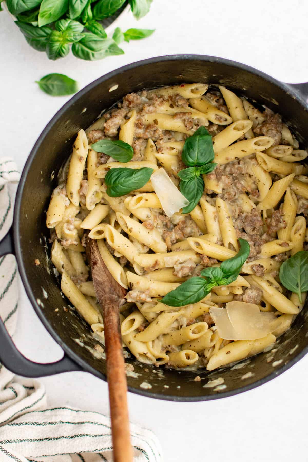 one pot sausage pesto pasta in a pot garnished with fresh basil