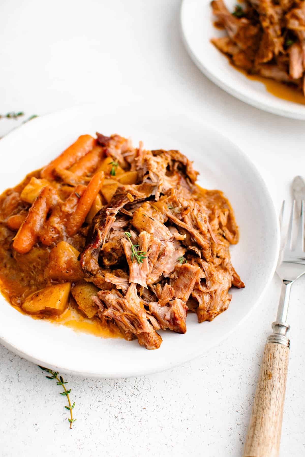 braised apple cider pork roast on a plate with carrots, potatoes and gravy