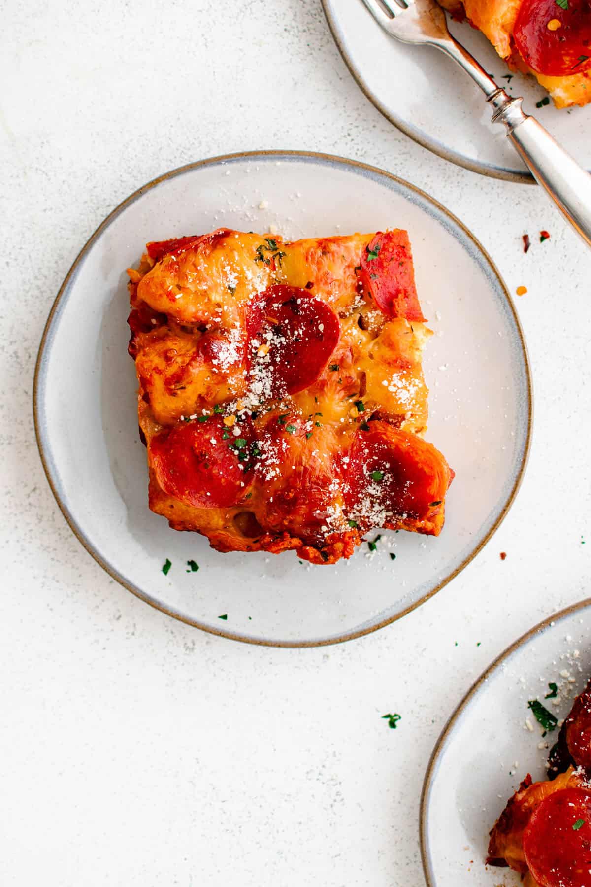 a piece of bubble up pizza on a plate with a light dusting of powdered parmesan cheese and fresh basil as garnish