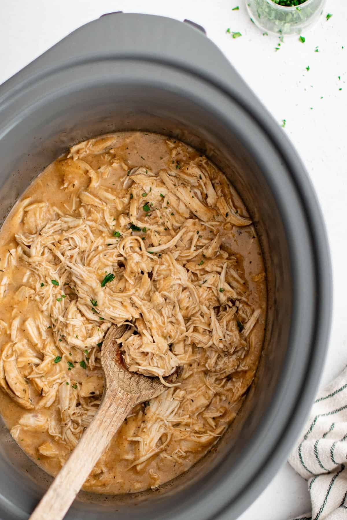 crockpot chicken and gravy in a crockpot with a wooden spoon
