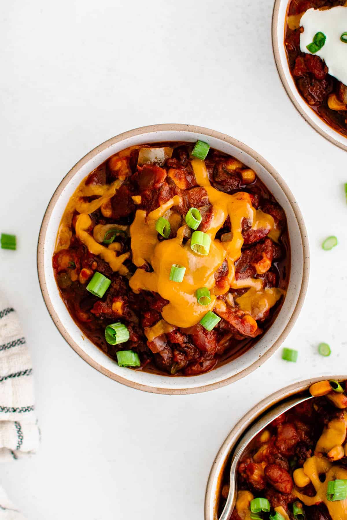vegetarian chili in a bowl with melted cheddar cheese and green onions